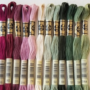 May include: Ten spools of DMC embroidery floss in various shades of red, pink, beige, green, and brown. The spools are labeled with the DMC color numbers: 915, 902, 315, 316, 778, 712, 524, 522, 934, 520, 336, and 3364.