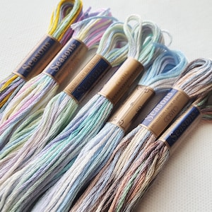 May include: Six spools of embroidery floss in various pastel colors, including pink, blue, green, and yellow. Each spool is labeled "Seasons" and "Cosito" with the text "100% Cotton Made in Japan".
