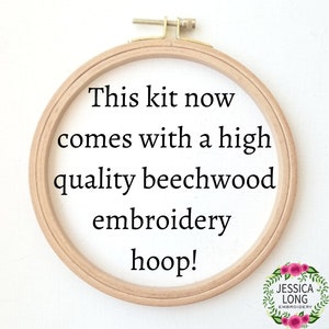 Puede incluir: Primer plano de un aro de bordado de madera con el texto "This kit now comes with a high quality beechwood embroidery hoop!" impreso en la tela dentro del aro.