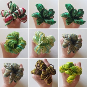 May include: Nine different colors of embroidery floss are twisted together to create a flower shape. The floss is arranged in a circular pattern with the ends of the floss coming together in the center. The colors of the floss are red, white, green, blue, yellow, brown, and black.