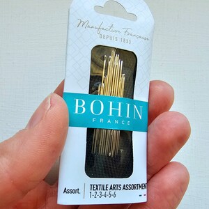 May include: A package of Bohin Textile Arts Assortment needles, size 1-2-3-4-5-6, made in France. The package is white with blue and red accents and features the Bohin logo.