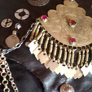 May include: A black leather belt with a gold and silver ornate design. The belt is decorated with chains, beads, and metal accents.