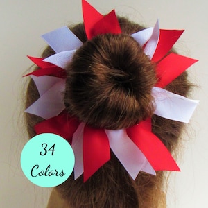 May include: A red and white hair bow with 34 colors available. The bow is made of ribbon and is tied around a bun.