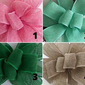 May include: Four different colors of burlap ribbon bows. The bows are arranged in a grid pattern. The colors are pink, teal, green, and beige.