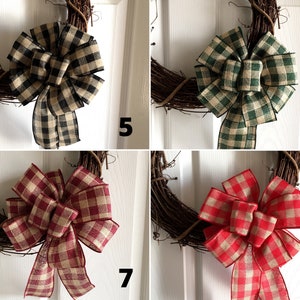 May include: A collection of four grapevine wreaths, each adorned with a large, plaid fabric bow. The bows vary in color, including black and tan, green and tan, burgundy and tan, and red and tan. The wreaths are displayed against a white door.