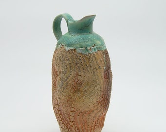 Wood fired ceramic pitcher with textured sides.