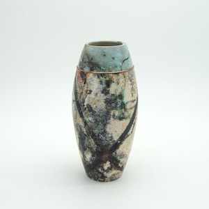 May include: A handcrafted ceramic vase with a unique, textured surface. The vase features a blend of colors, including beige, green, and black, with a turquoise rim and a copper band. The design has an abstract, artistic quality, suitable for home decor.