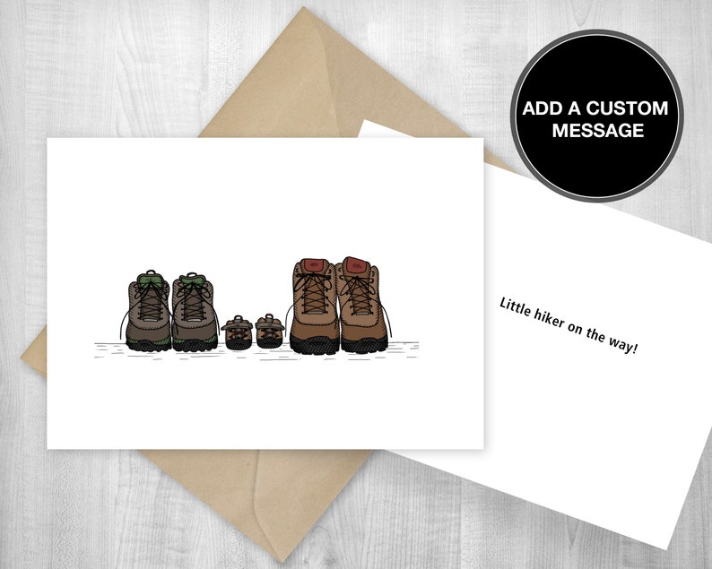 May include: A white card with a drawing of four pairs of hiking boots. The boots are brown, green, and tan. The card says "Little hiker on the way!" and "ADD A CUSTOM MESSAGE".