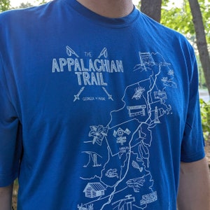 May include: A royal blue t-shirt with a white graphic design of the Appalachian Trail. The graphic includes the text "The Appalachian Trail" and "Georgia to Maine".