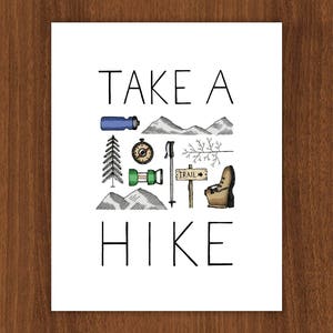 May include: A white print featuring the text "TAKE A HIKE" and illustrations of hiking equipment. The image includes a water bottle, compass, mountains, a pine tree, hiking poles, and a trail sign. The artwork is in black, green, blue, and brown.