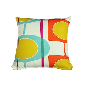May include: A white pillow with a geometric pattern in shades of yellow, orange, teal, and pink.