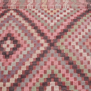 K&ouml;nnte beinhalten: Ein Vintage-Teppich mit einem geometrischen Muster in Rot-, Rosa-, Gr&uuml;n- und Schwarzt&ouml;nen. Der Teppich hat eine gewebte Textur und einen abgenutzten Look.