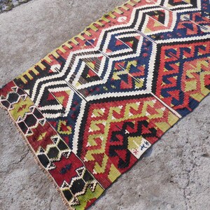 May include: A colorful, geometric patterned rug with a traditional design. The rug features a mix of red, yellow, blue, black, and white colors.