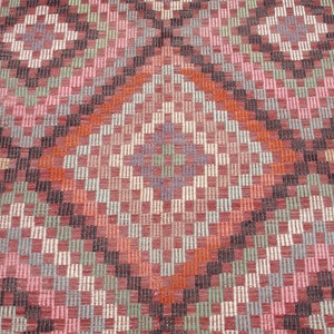 K&ouml;nnte beinhalten: Nahaufnahme eines gewebten Teppichs mit einem geometrischen Muster in den Farben Rosa, Rot, Orange, Gr&uuml;n und Schwarz.