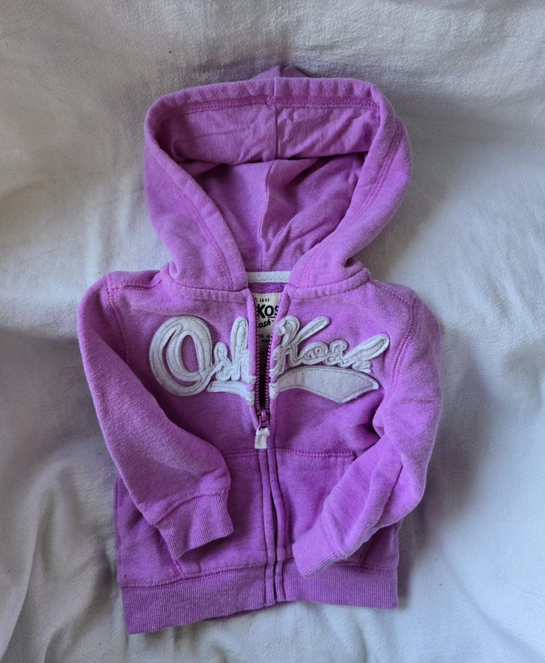 Może przedstawiać: Fioletowa bluza z kapturem zapinana na zamek błyskawiczny z białym logo "Old Navy" z przodu.