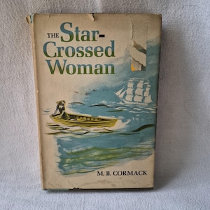 May include: Vintage paperback book titled "The Star-Crossed Woman" with a cover illustration of a person in a boat on the water, a sailboat, and a cliff. The title is in green and black, with the author's name, M.B. Cormack, at the bottom.