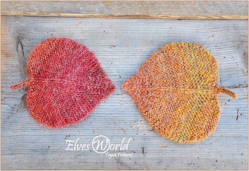 K&ouml;nnte beinhalten: Zwei gestrickte Untersetzer in Blattform, einer rot und einer orange, auf einer Holzoberfl&auml;che. Die Untersetzer sind aus einem strukturierten Garn gefertigt und haben ein leicht flauschiges Aussehen. Der Text "Elves World Toys & Patterns" ist am unteren Rand des Bildes sichtbar.