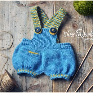 May include: Knitted blue baby dungarees with yellow and blue striped straps and yellow trim. The dungarees have a small pocket on the front. The image also includes yarn and knitting needles.