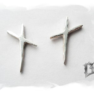May include: Two silver cross earrings with a rough, textured finish.