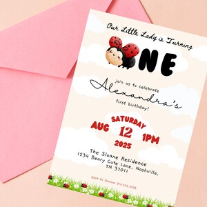 Op de afbeelding: Een lichtbeige uitnodigingskaart met een roze envelop. De kaart heeft een lieveheersbeestjesthema met de tekst "Our Little Lady is Turning ONE" en details voor een eerste verjaardag, inclusief datum, tijd en locatie.