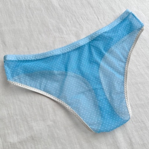 Könnte beinhalten: Hellblaue Unterwäsche mit weißem Tupfenmuster. Die Kanten sind mit weißer Spitze verziert. Das Kleidungsstück besteht aus einem transparenten, leichten Stoff.