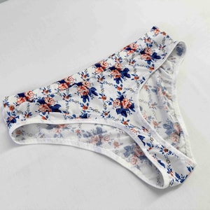 Puede incluir: Bragas de encaje blancas con un estampado floral en tonos azules, rojos y blancos.