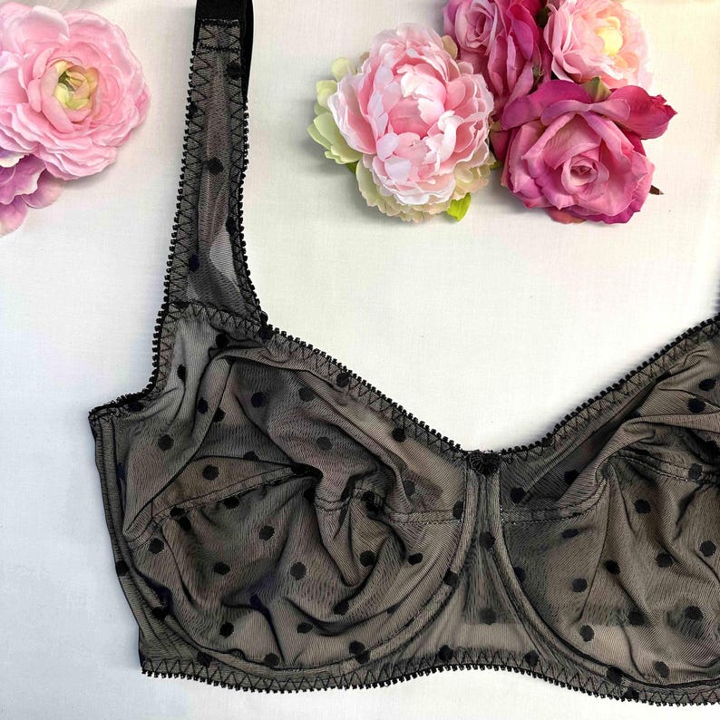 May include: Black polka dot lace bra with adjustable straps. The bra has a delicate, feminine design.