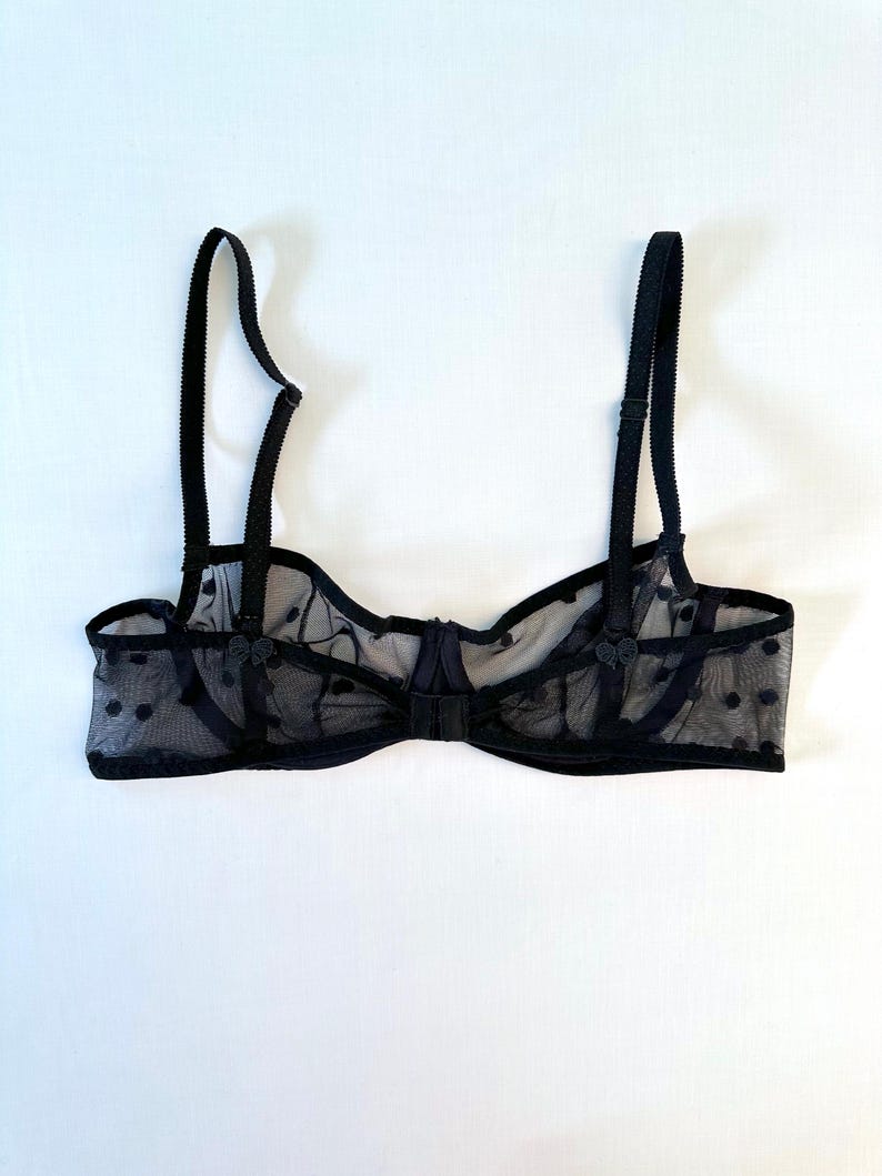 May include: Black polka dot mesh bra with adjustable straps and a hook and eye closure.