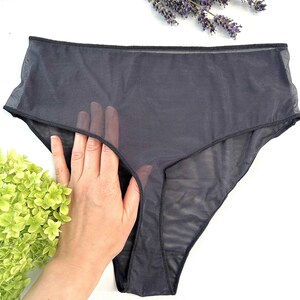 Op de afbeelding: Donkergrijze, doorschijnende high-waisted onderbroek. Het ondergoed is gemaakt van een lichtgewicht, doorzichtige stof. De afbeelding bevat ook takjes lavendel en groene bladeren.