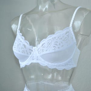 May include: White lace bra with adjustable straps. The bra has a delicate floral pattern and a smooth, seamless cup.