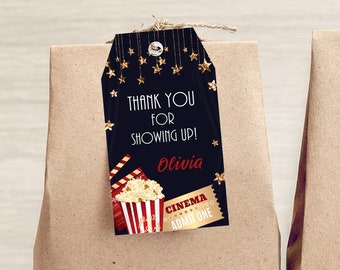 Op de afbeelding: Twee bruine papieren zakken met cadeau-etiketten met een gouden ster en popcorn-thema. De etiketten zeggen "Bedankt voor je komst! Olivia" en "Bioscoop Toegangskaartje".