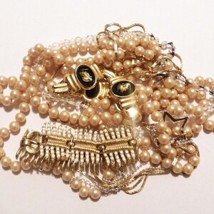 May include: A collection of vintage jewellery, featuring faux pearl necklaces, gold-toned metal clasps, and a star-shaped charm. The pieces are in shades of gold, cream, and pearl, creating a classic and elegant look. Measurements are not applicable.
