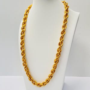 Puede incluir: Un collar de cadena de oro grueso con un diseño de cuerda. El collar se muestra en un maniquí blanco.