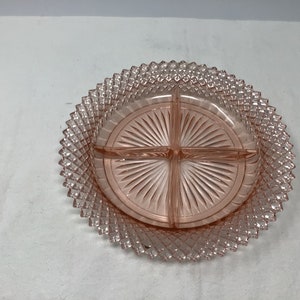 May include: A pink glass divided serving dish with a diamond pattern on the outer edge and a sunburst pattern on the inside.