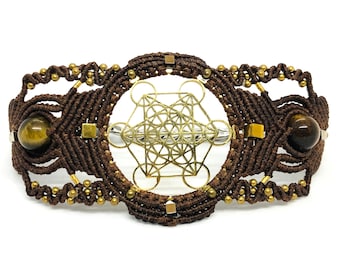 May include: Brown macrame bracelet with gold beads and a gold metal geometric design. The bracelet features two tiger's eye stones.