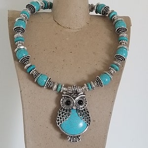 May include: A turquoise and silver necklace with an owl pendant. The owl has black eyes and a turquoise body.