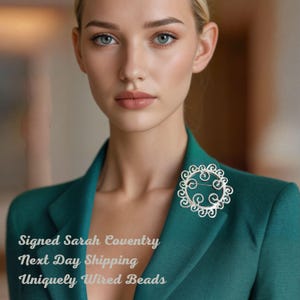 Broche vintage de Sarah Coventry, 1971, con niebla plateada, filigrana calada en tono plateado y corona de espirales.