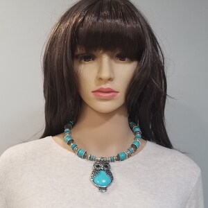 May include: A turquoise and silver owl pendant necklace. The necklace is made of turquoise beads and silver accents. The owl pendant has a turquoise stone in the center.