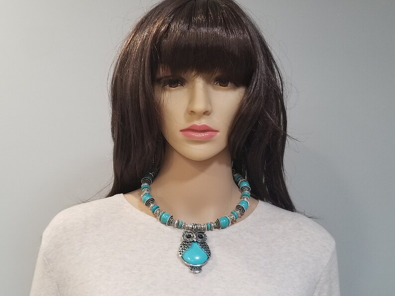 May include: A turquoise and silver owl pendant necklace. The necklace is made of turquoise beads and silver accents. The owl pendant has a turquoise stone in the center.