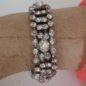 Peut inclure: Un bracelet argent&eacute; avec plusieurs rang&eacute;es de strass transparents. Le bracelet est en m&eacute;tal et a un design d&eacute;licat et f&eacute;minin.