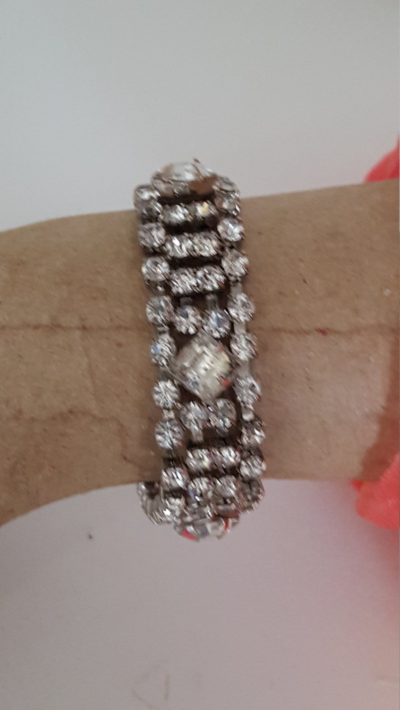 Peut inclure: Un bracelet argent&eacute; avec plusieurs rang&eacute;es de strass transparents. Le bracelet est en m&eacute;tal et a un design d&eacute;licat et f&eacute;minin.