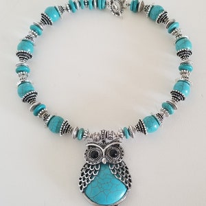 May include: A turquoise and silver necklace with an owl pendant. The owl has a turquoise body with silver detailing and black eyes.