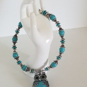 May include: Turquoise and silver owl necklace with a turquoise and silver bead chain.