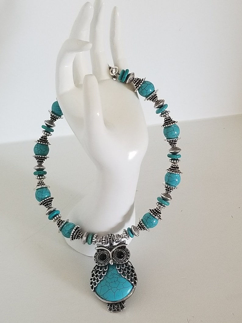 May include: Turquoise and silver owl necklace with a turquoise and silver bead chain.