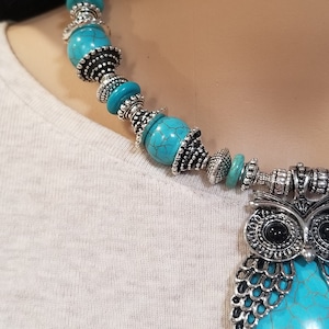 May include: A turquoise and silver owl pendant necklace with a turquoise stone and silver beads.