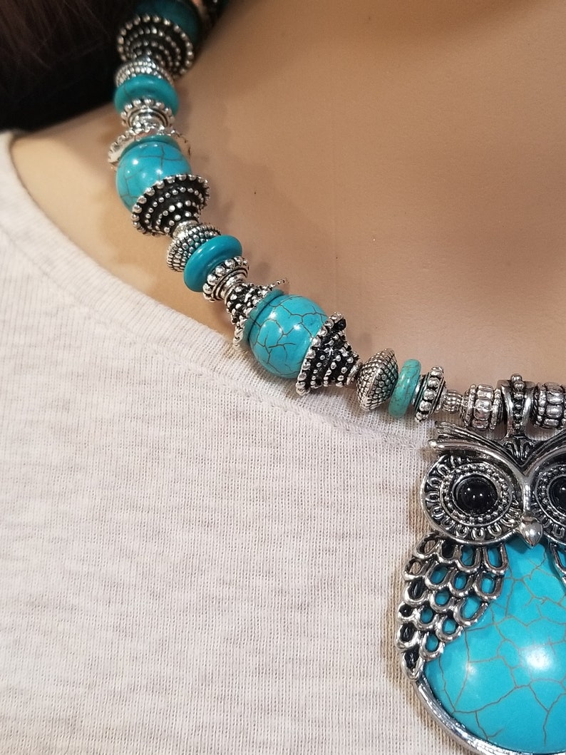 May include: A turquoise and silver owl pendant necklace with a turquoise stone and silver beads.