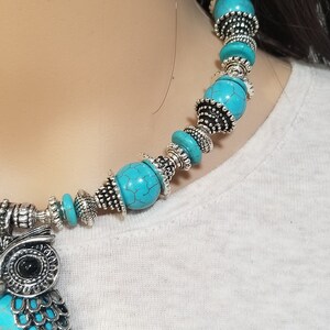 May include: A turquoise and silver owl pendant necklace. The necklace features a large owl pendant with turquoise stones and silver accents. The necklace is made of turquoise beads and silver spacers.
