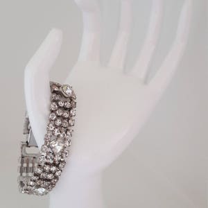 Peut inclure: Un bracelet argent&eacute; avec une rang&eacute;e de strass transparents. Le bracelet est sur une main de mannequin blanche.