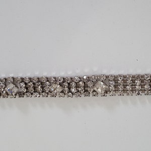 Peut inclure: Un bracelet argent&eacute; avec une rang&eacute;e de strass transparents et une fermeture &agrave; fermoir.