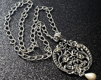 Collar vintage Avon de estilo barroco victoriano en tono plateado, con colgante de perlas sintéticas en forma de lágrima calada en metal, pieza de moda llamativa y esculpida.